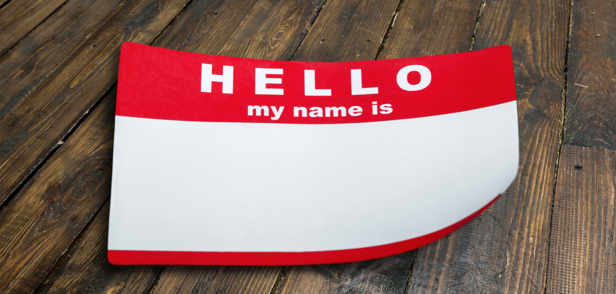 'hello my name is..." red and white sticker on wooden table